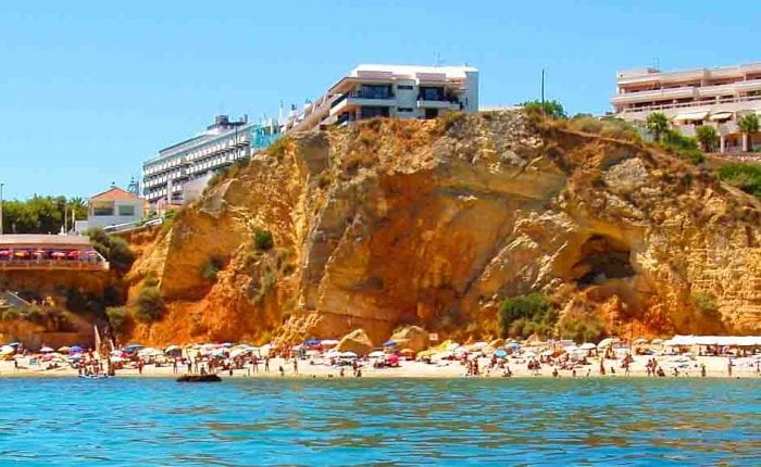 Stunning view of the Algarve coast in Portugal with golden cliffs, crystal-clear beach, and blue skies – one of the best places to live in Europe