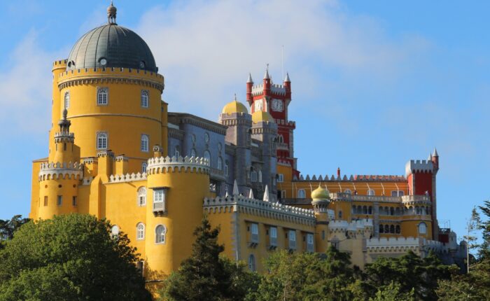 Colorful Pena Palace on a lush hilltop in Sintra, Portugal, surrounded by forests and misty skies — a fairytale landmark and UNESCO World Heritage site.
