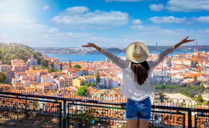 Panoramic view of Lisbon from Senhora do Monte Hill, showcasing red tile roofs, São Jorge Castle, and the Tagus River.