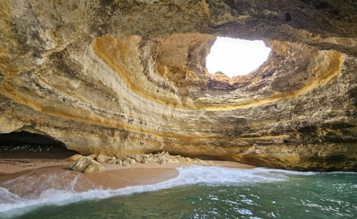 Benagil Cave in Algarve, Portugal with natural skylight and golden sand beach inside the sea cave
